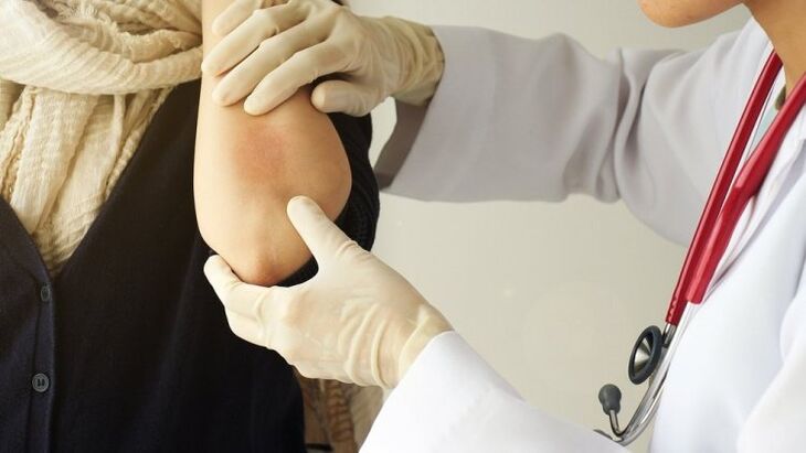doctor examines his elbow for psoriasis